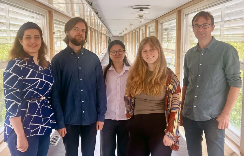 Group of smiling researchers in a corridor. Photo.