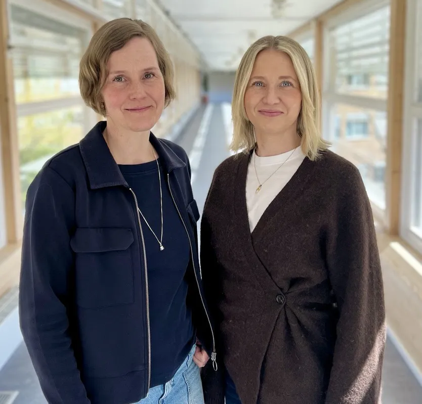 Two smiling women in a corridor. Photo.